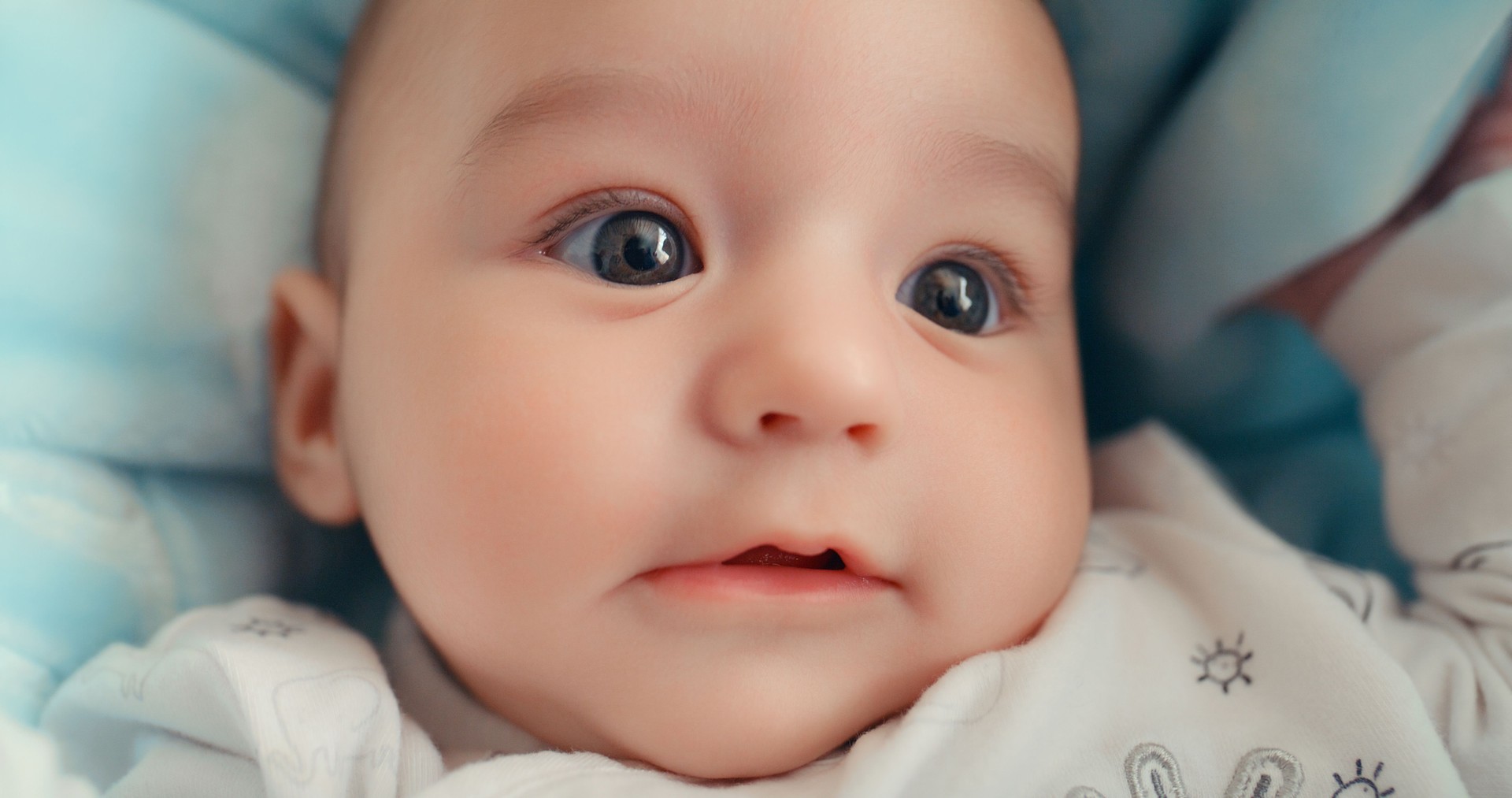 Cute, face and closeup of a baby in bed for sleep, relax or playing in the morning. Calm, adorable and a little child in the bedroom for rest, wake up from sleeping and innocent in a house from above